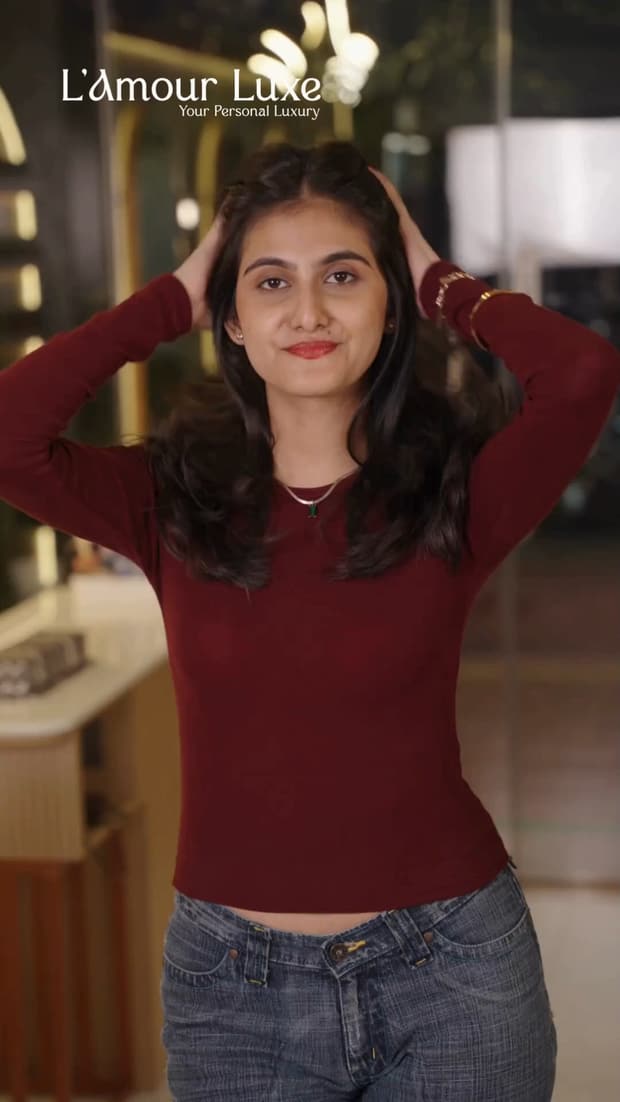 A client in a maroon top running both hands through freshly styled long dark hair.
